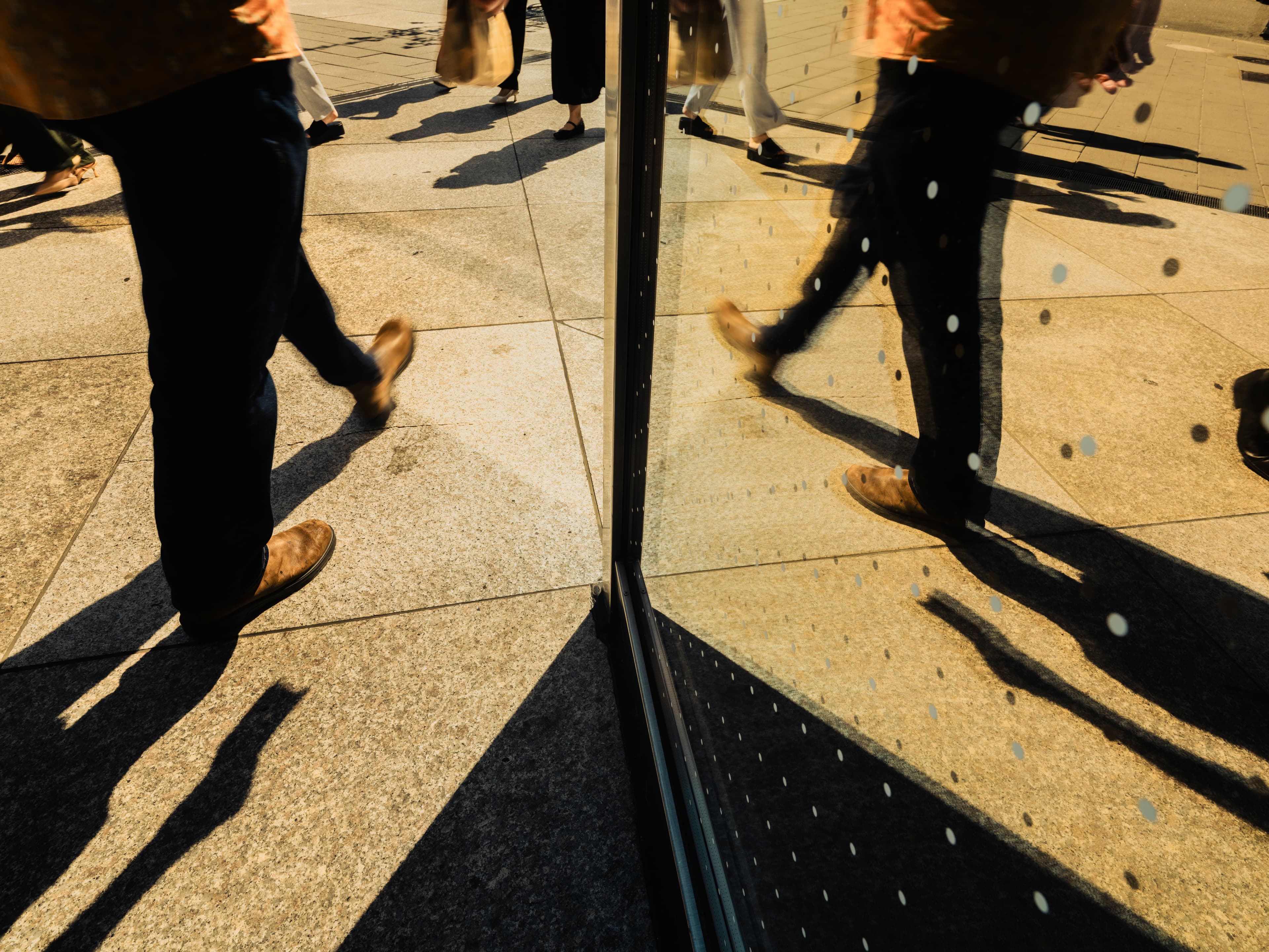 Reflection shot of people walking past a building window