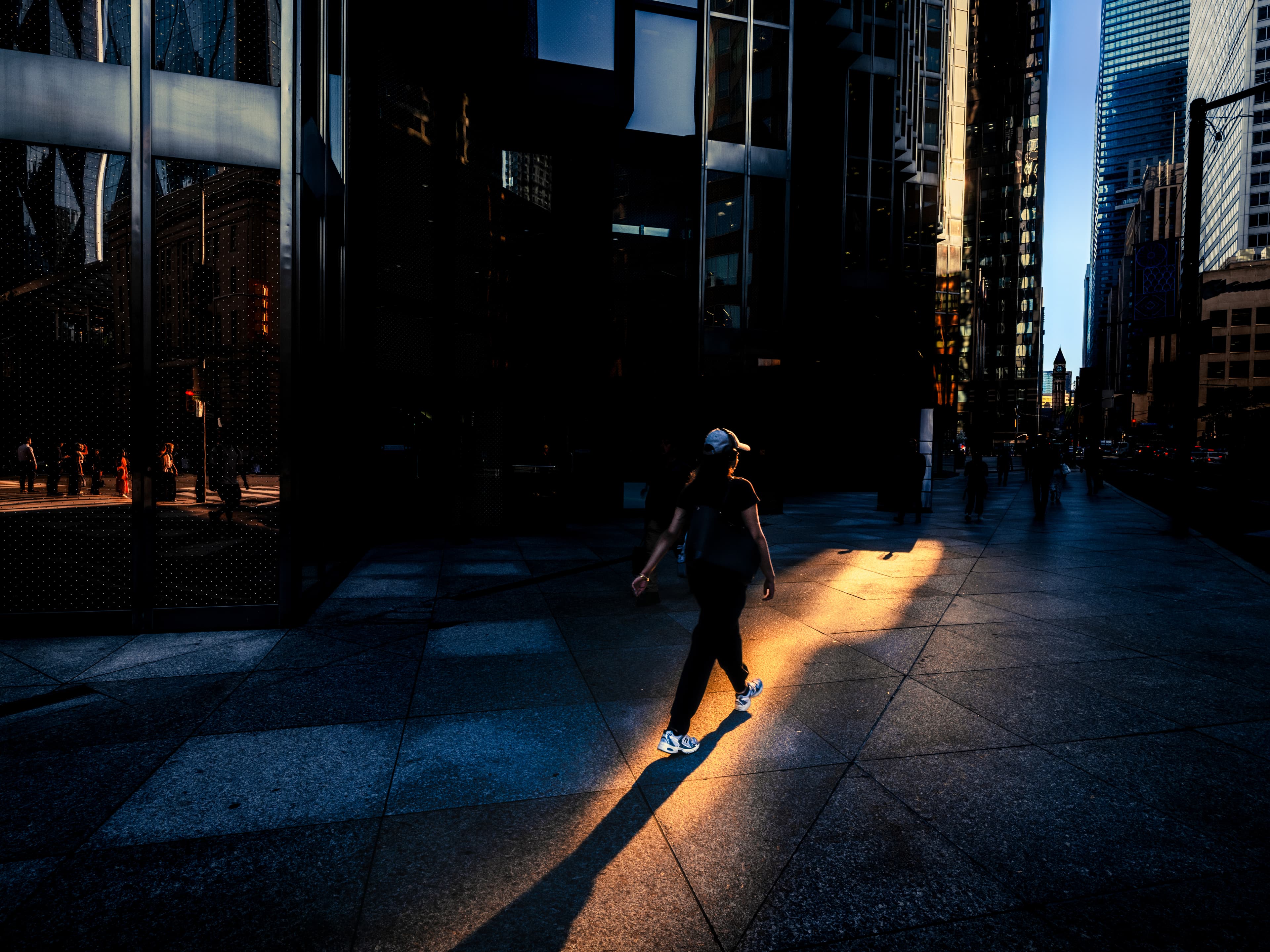 Person walking through reflected sunlight outside a downtown office