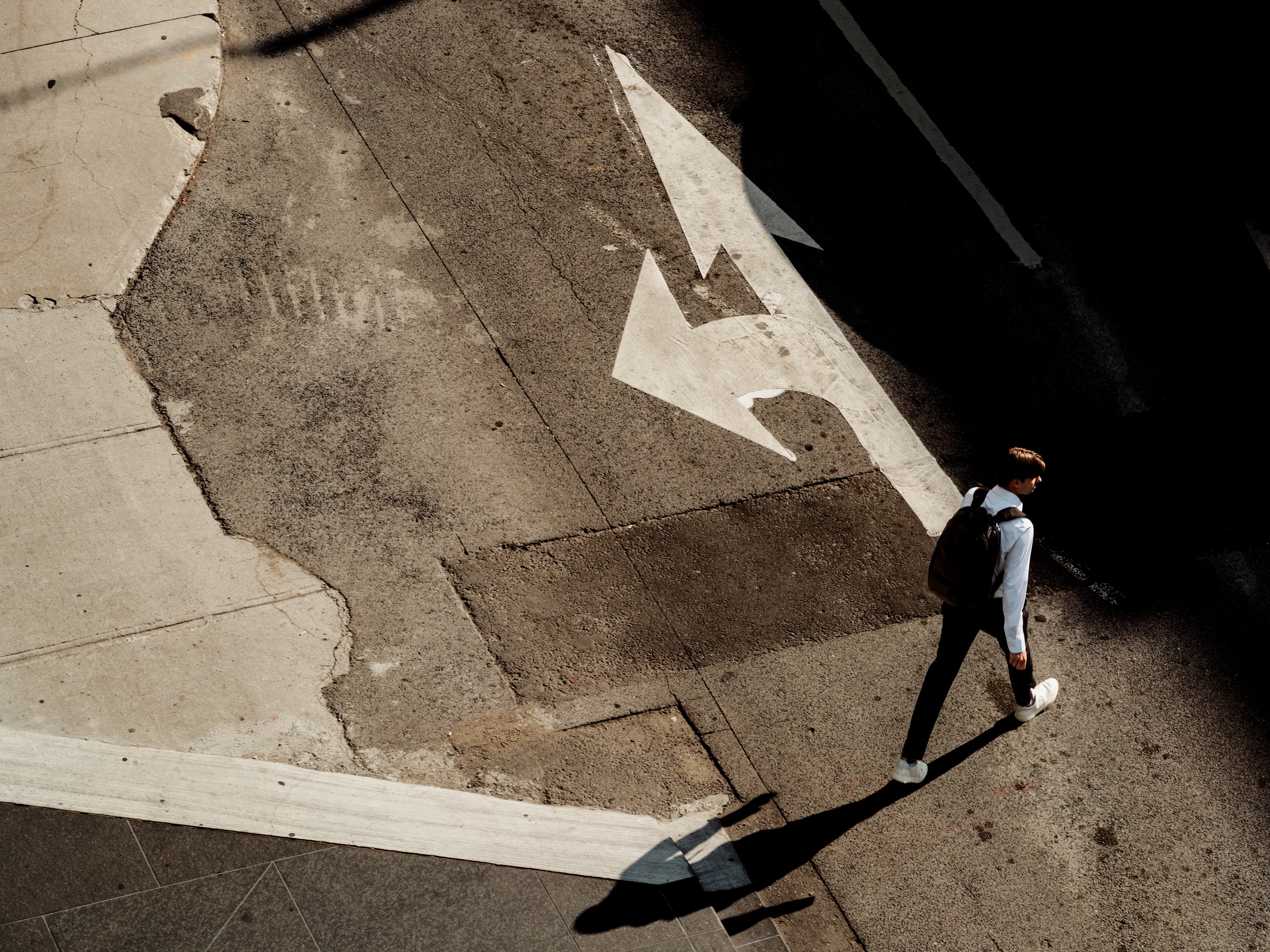 Overhead shot of a man walking across a right turn lane on a street