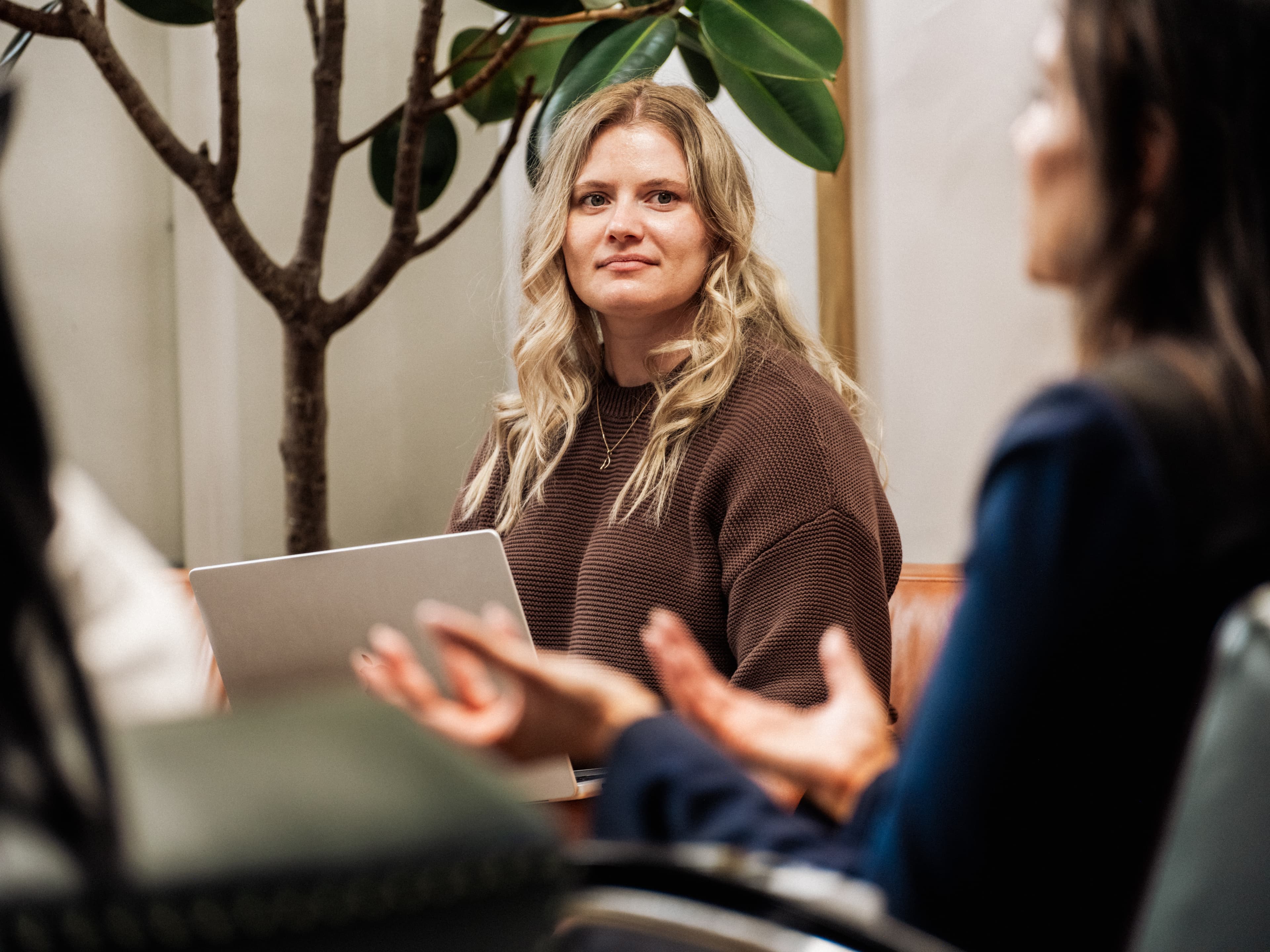 Woman with a laptop in a meeting looking to someone speaking