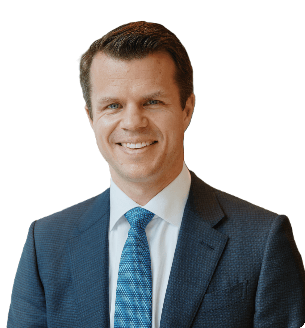 Smiling man in a blue suit and tie with short brown hair, against a white background.